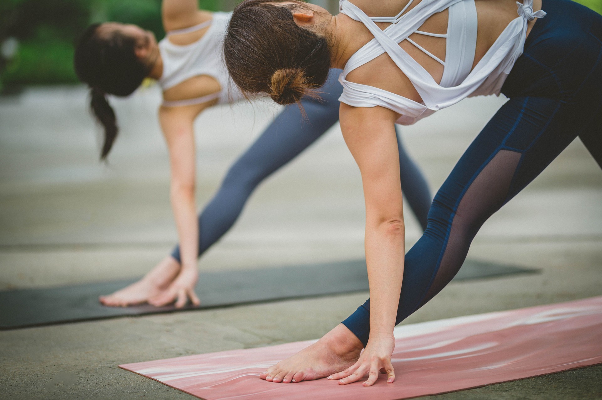 Two young fitness Asian women practicing yoga together relax in nature